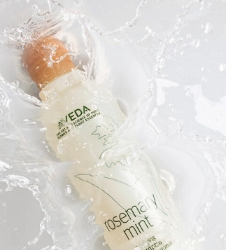 Aveda Rosemary Mint shampoo captured in water splash – Refreshing and sustainable haircare product featured at Eddine Belaid salon