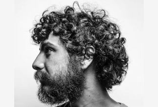 Men’s curly hairstyle with full beard styled by Eddine Belaid – Natural texture and artistic grooming in Switzerland